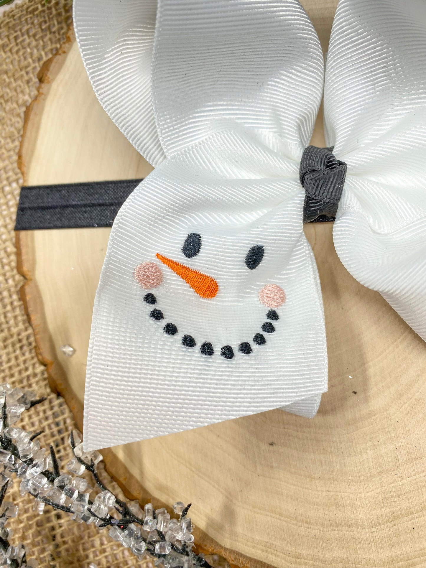 White Snowman Embroidered Headband on a wooden background