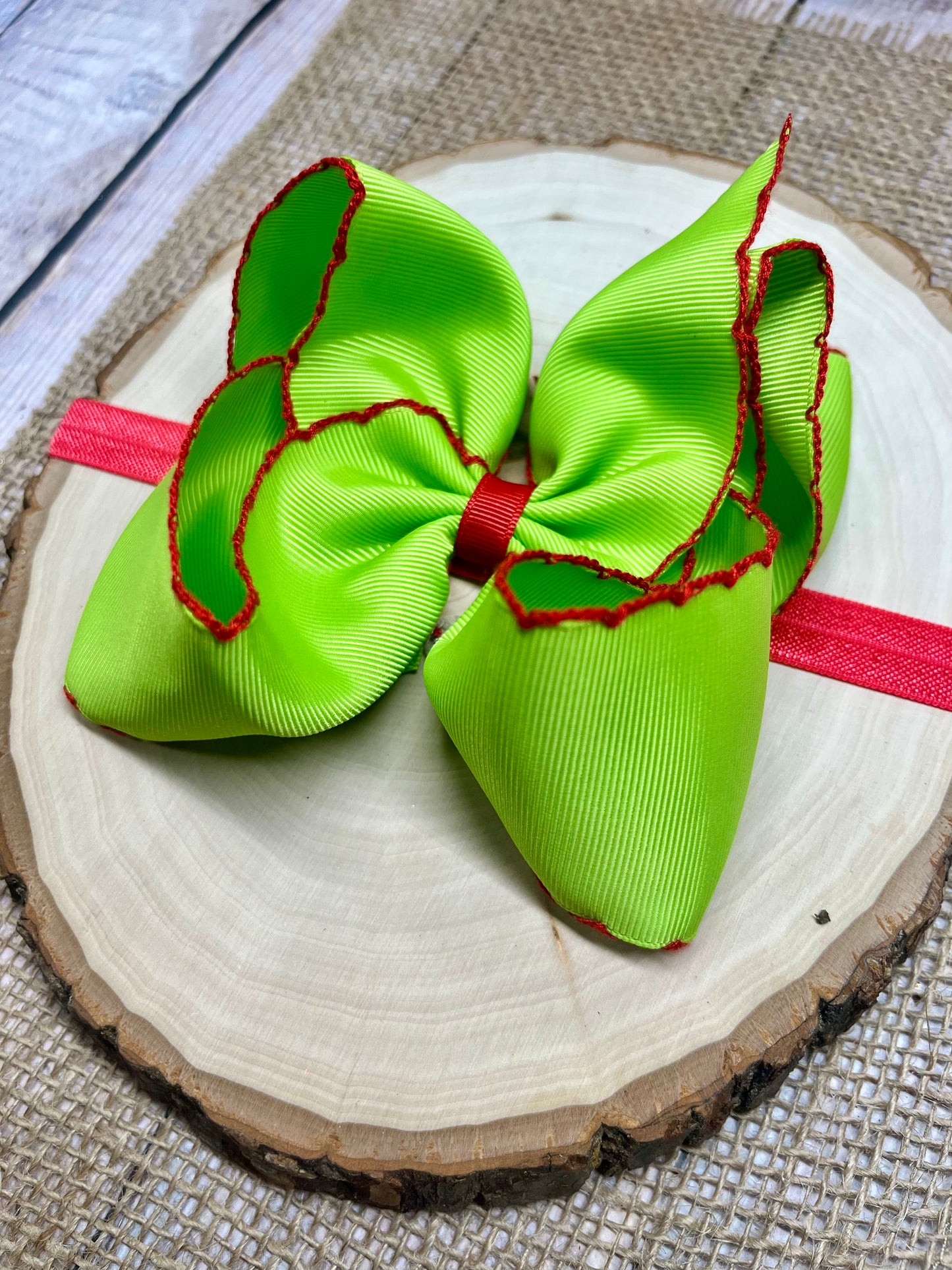Green hair bow with red accents on a wooden surface