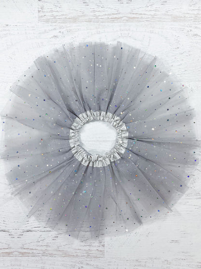 This soft grey tutu is made from polyester tulle, with a silver satin elastic waistband.  The top of three layers is covered with silver sparkle dots in varying sizes.  