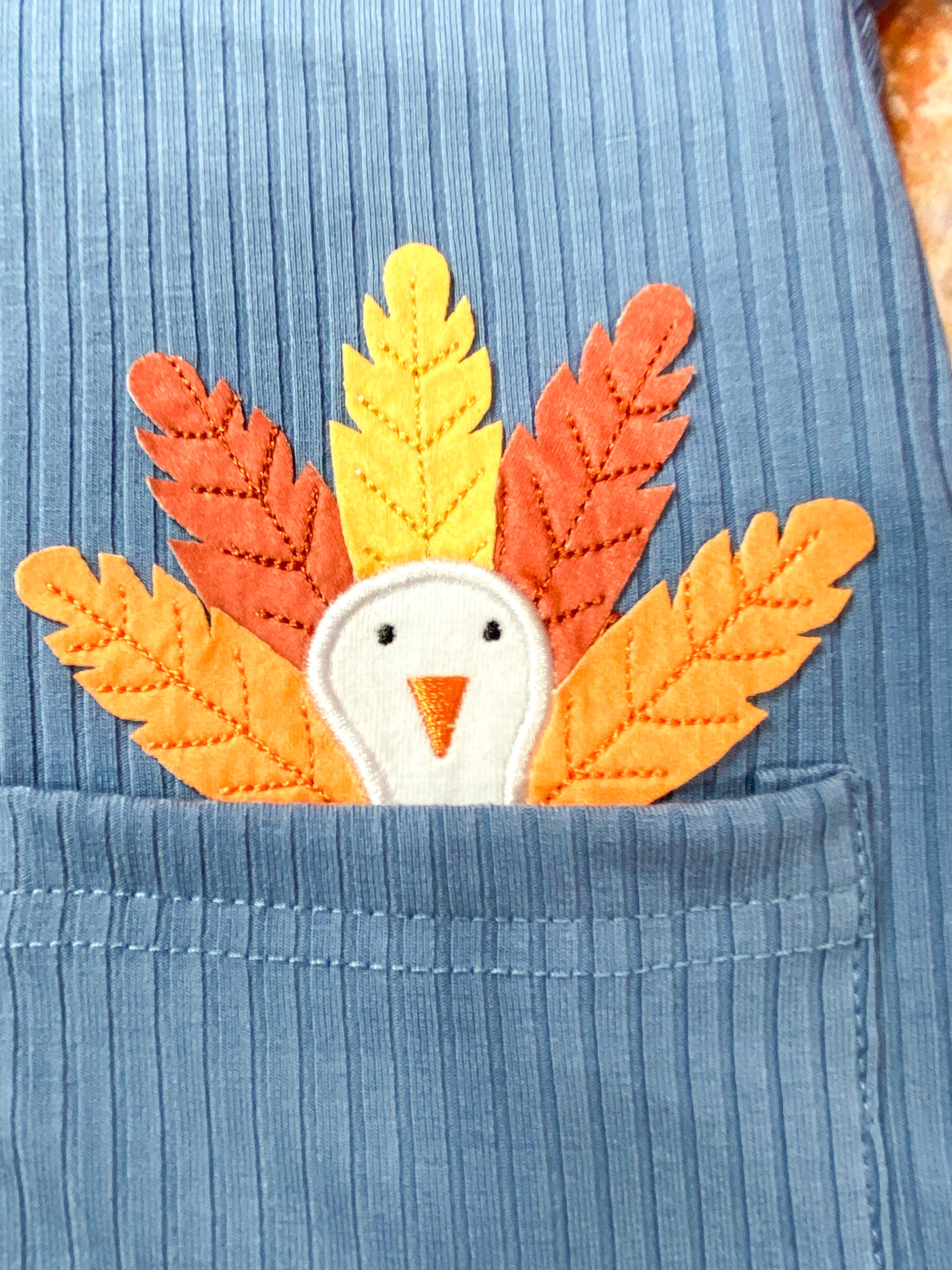 close up of turkey applique peaking out of the pocket on hoodie
