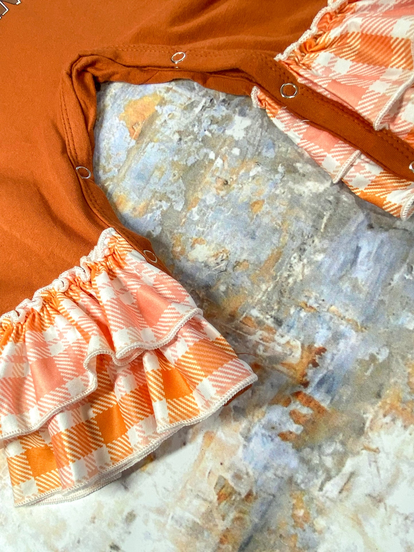 close up photo showing ruffles at end of pant legs and snaps for easy changing