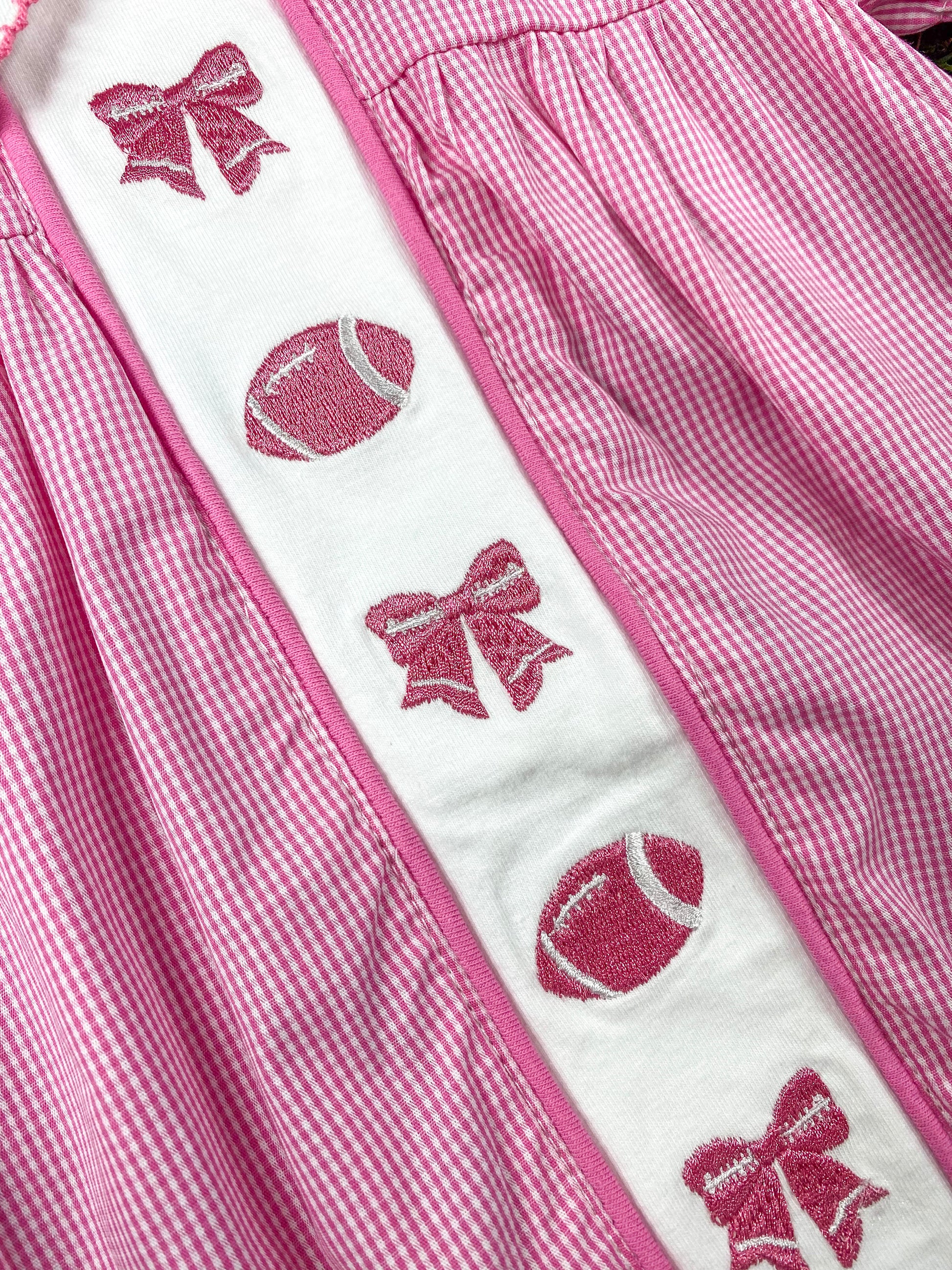 close up of the bows and football embroideries on front of the romper
