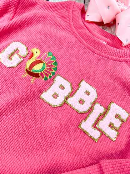 close up of the gobble chenille on front of shirt showing a colorful turkey as the "o"
