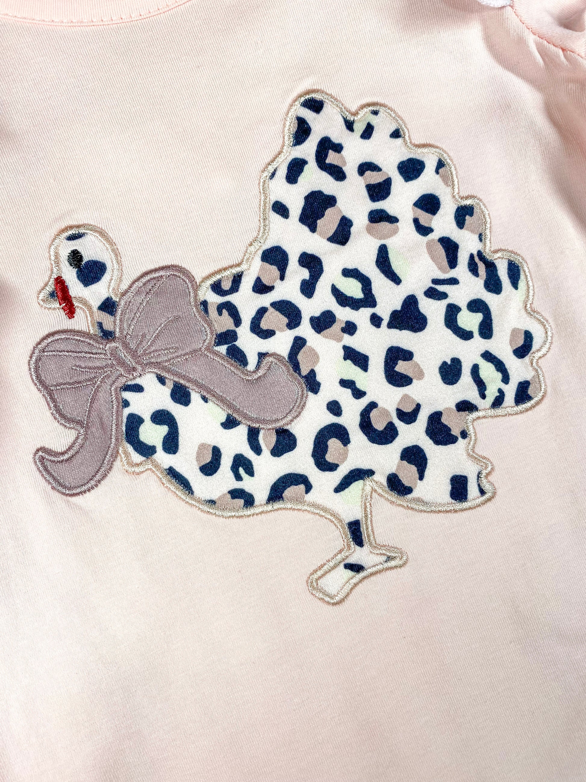 close up of the chicken in animal print with a bow around it's neck