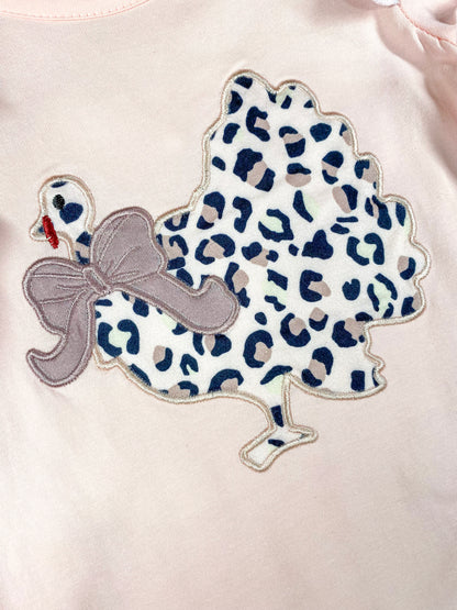 close up of the chicken in animal print with a bow around it's neck