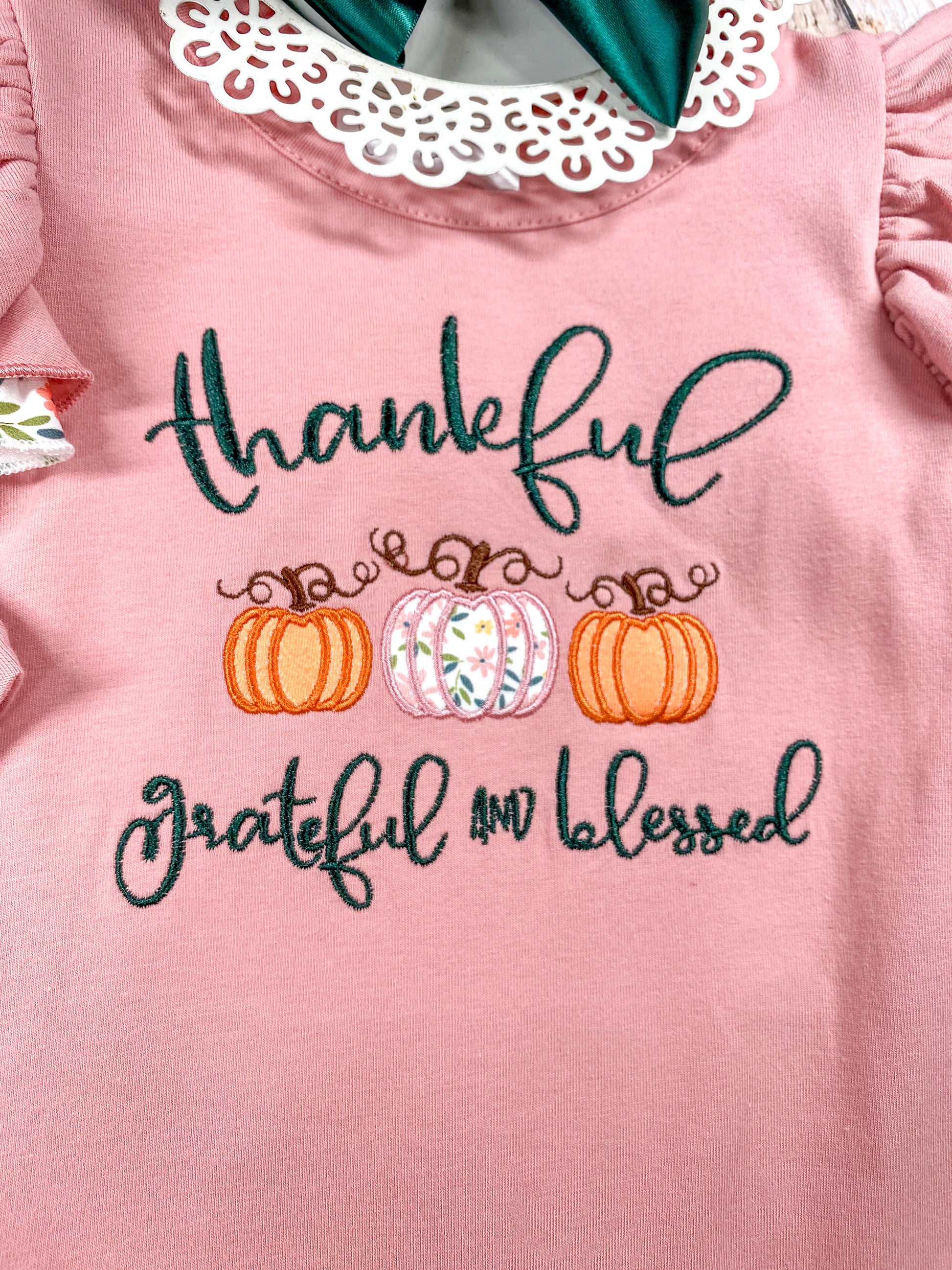 close up of the embroidery on front saying "thankfuk grateful and blessed" in cursive and 3 pumpkins