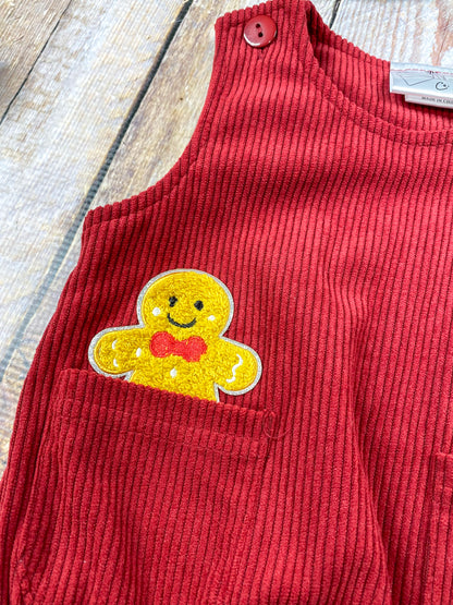 close up of one of the gingerbread man appliques coming out of pocket on front of romper