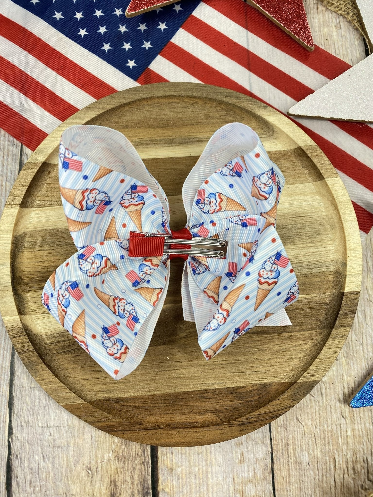 back of Hair bow with ice cream cone pattern on a wooden plate with an American flag in the background