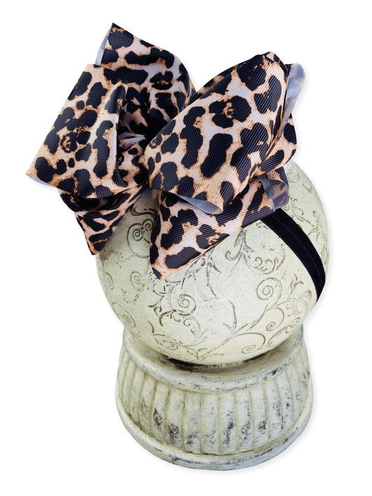 Leopard print bow headband on a white pedestal