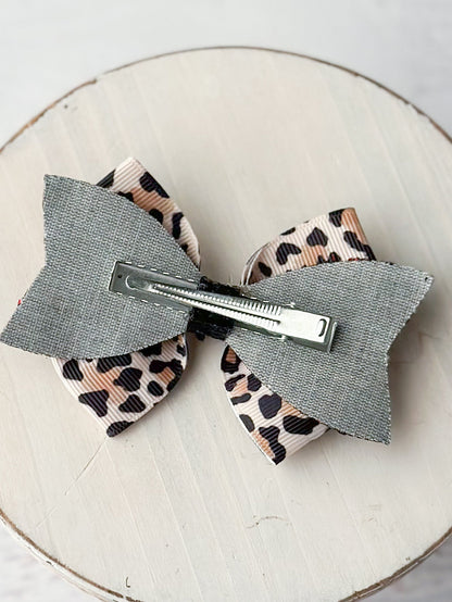 Back of animal print glitter hair bow showing single prong alligator clip