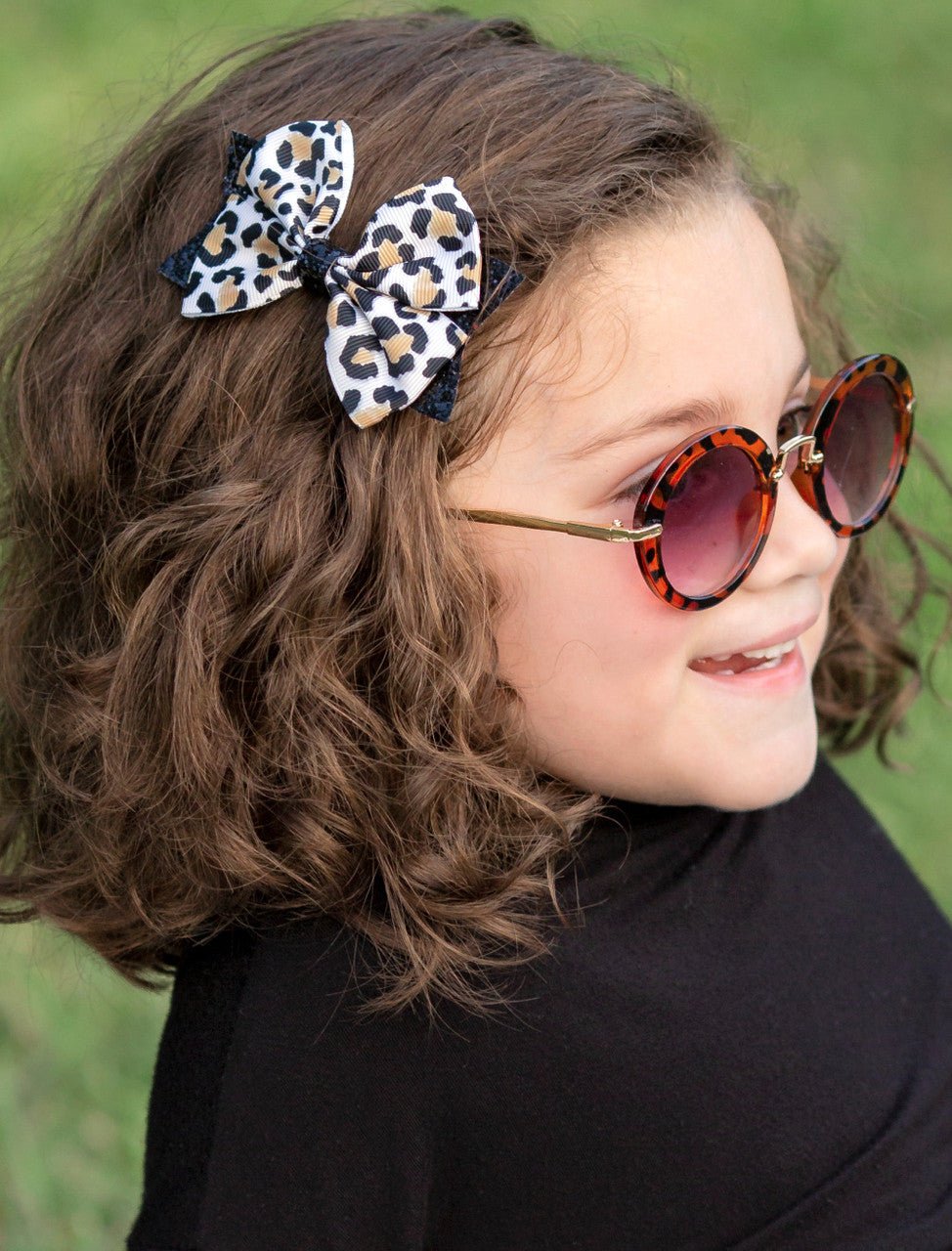 Close-up of an animal print and black glitter hair bow worn in a girl's hair