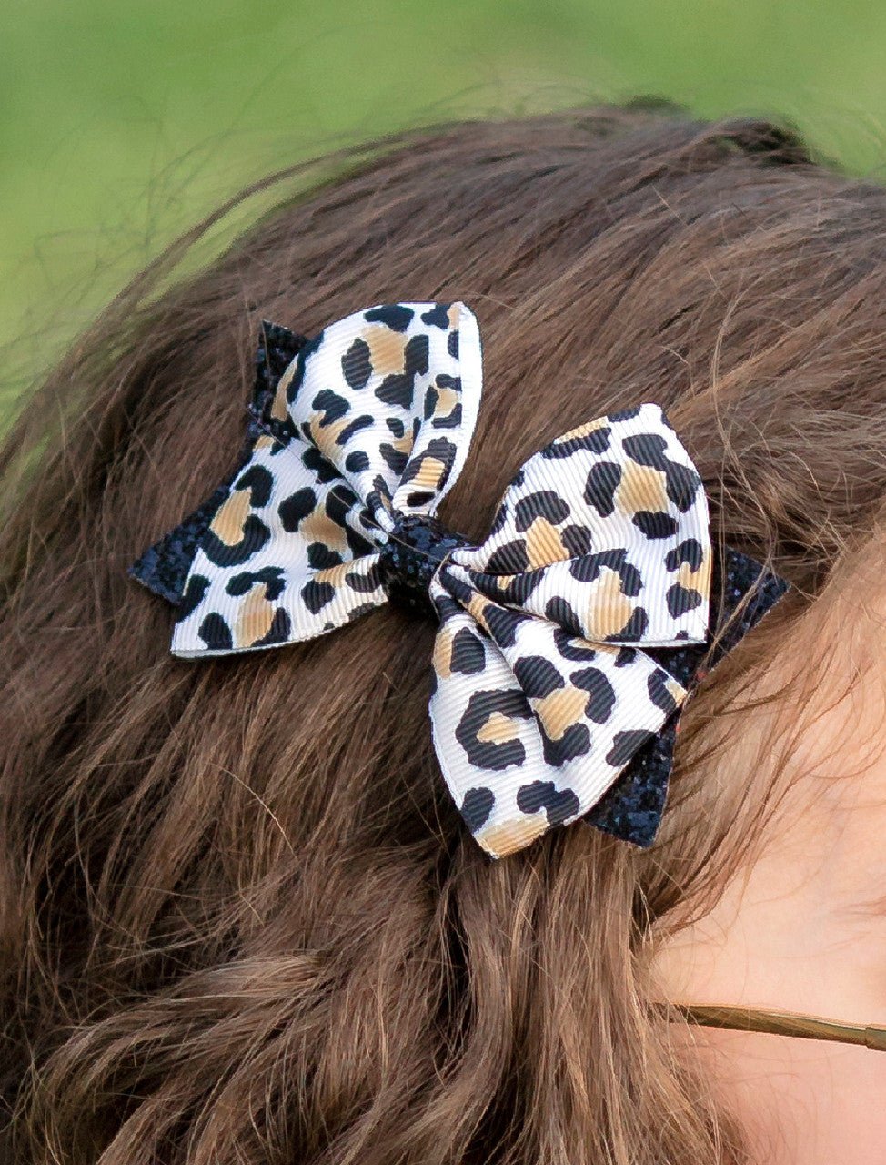 Girl wearing an animal print and black glitter hair bow