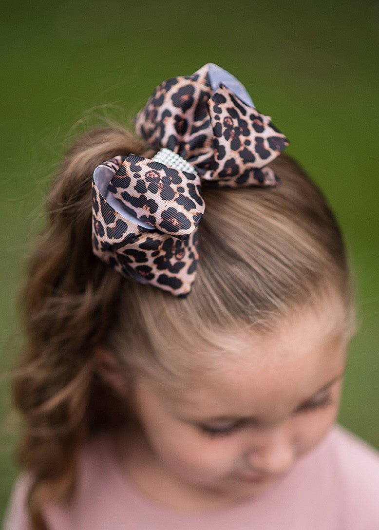 Girl wearing a 4 inch leopard print rhinestone center hair bow