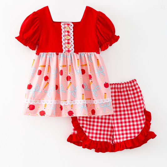 Red and pink children's outfit with checkered shorts on a white background