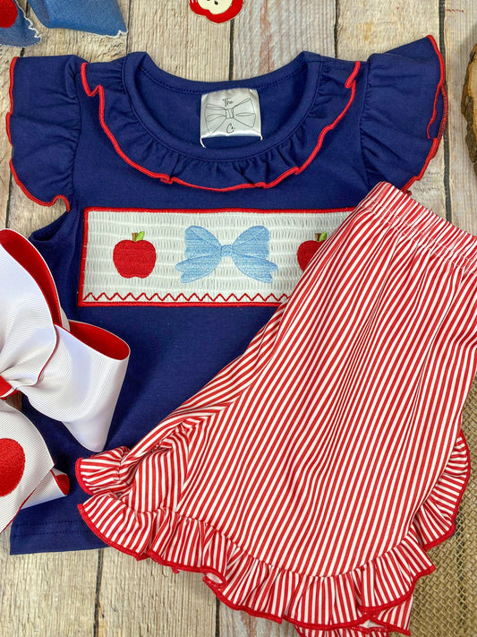 Navy top with red and white accents and red striped shorts on a wooden background