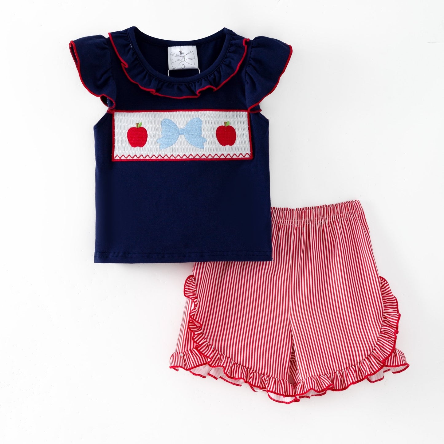 Navy top with red and white accents and red striped shorts on a white background