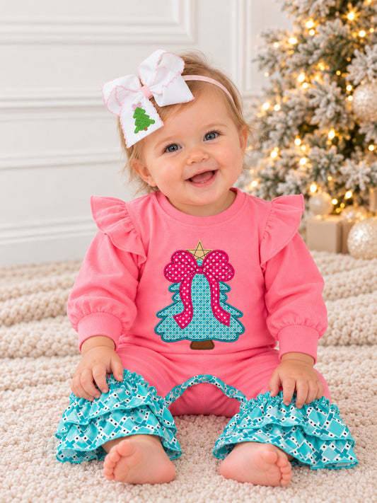 model wearing a girl pink Christmas romper with bow tree appliqué and teal ruffles on a rug