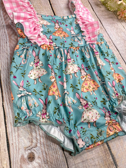 snap detail of romper with bunny print on a wooden surface