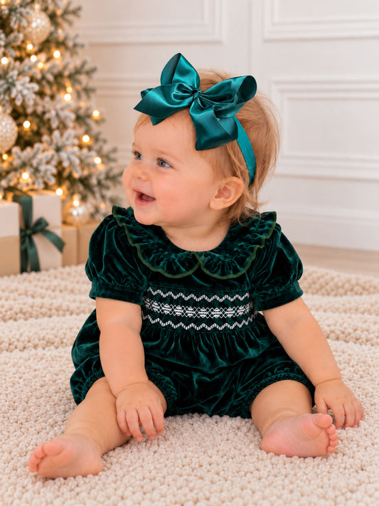 Baby wearing a green baby velvet smocked Peter Pan bubble romper with ruffled collar on rug