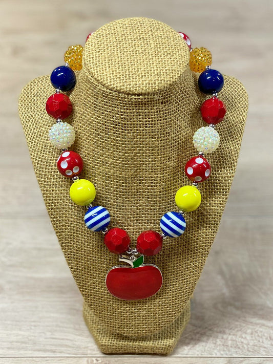 Red apple pendant chunky bead necklace with red polka dot, blue and white striped, white rhinestone, solid red, blue, and yellow beads, with a heart toggle closure. - Alternative view