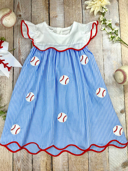 Girl's baseball dress with blue and white striped pattern and red trim on awooden background