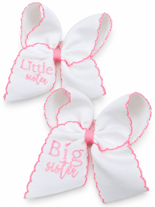 Coordinating white Big Sister and Little Sister hair bows with pink embroidery, scalloped stitched edges and matching pink centers on a white background.