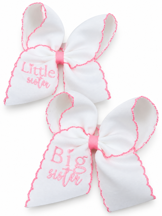 Coordinating white Big Sister and Little Sister hair bows with pink embroidery, scalloped stitched edges and matching pink centers on a white background.