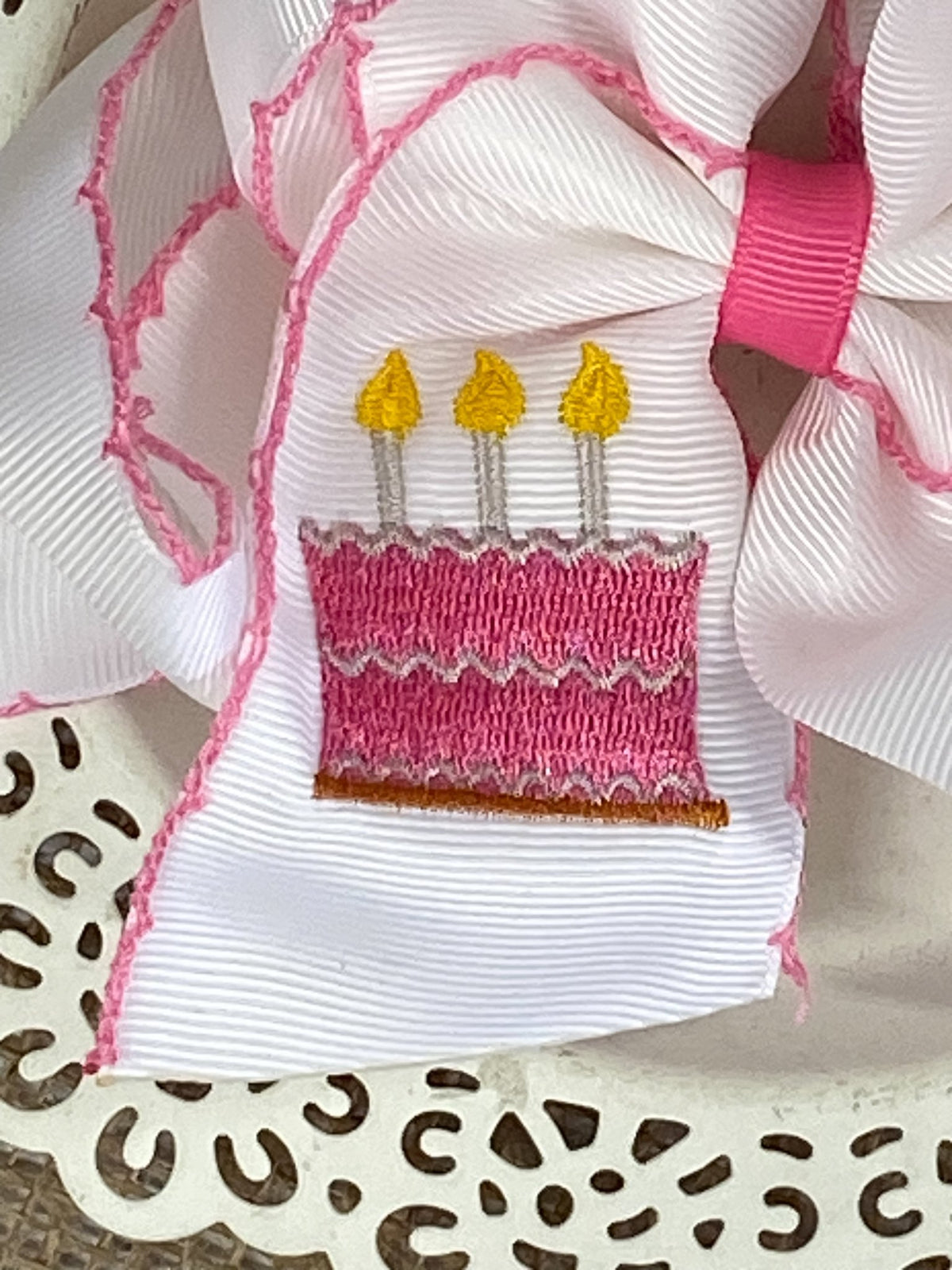 Close-up of birthday cake embroidery and moonstitch detail on bow headband