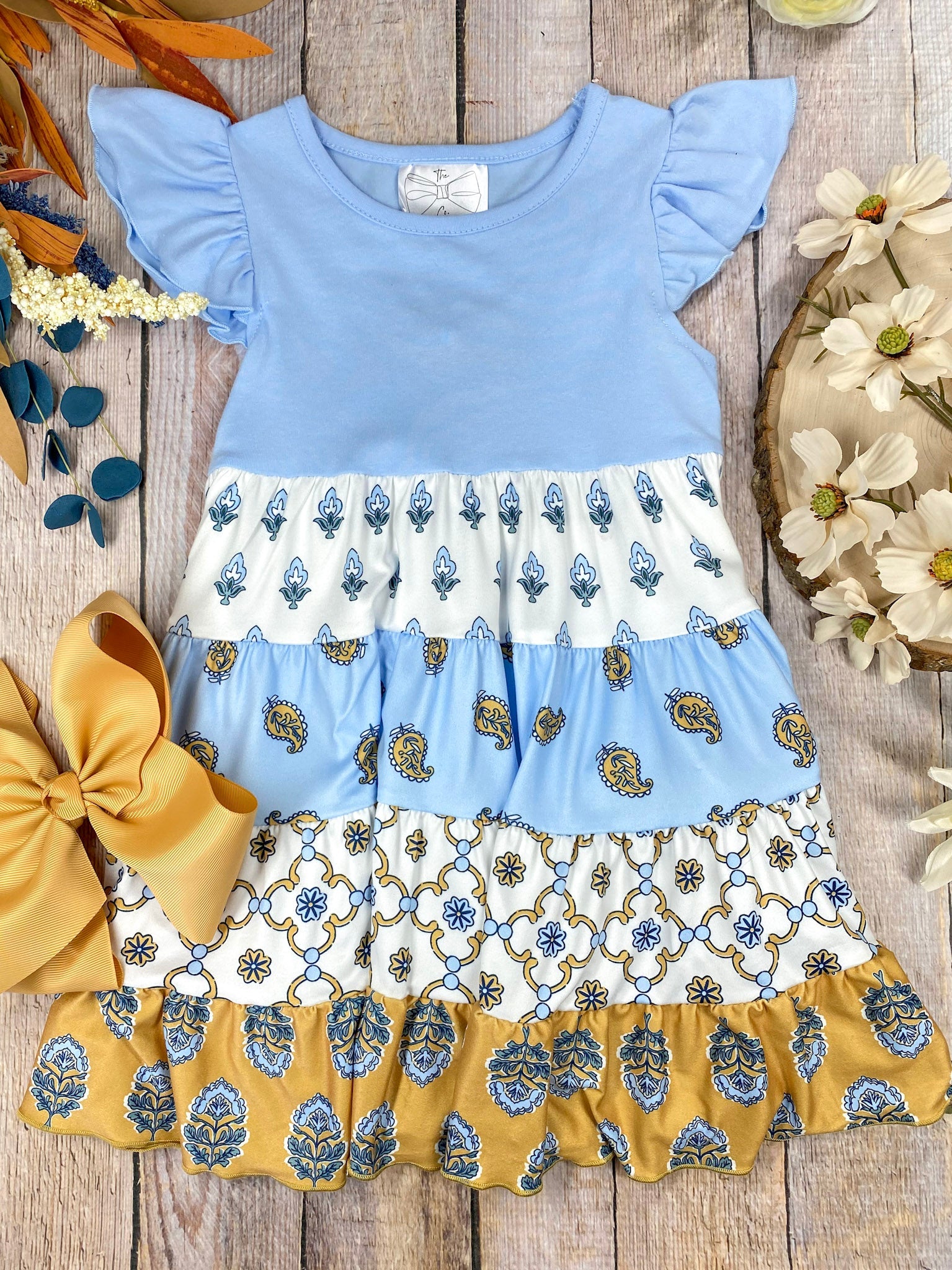 Boutique Boho Children's dress with blue top and floral skirt on a wooden background