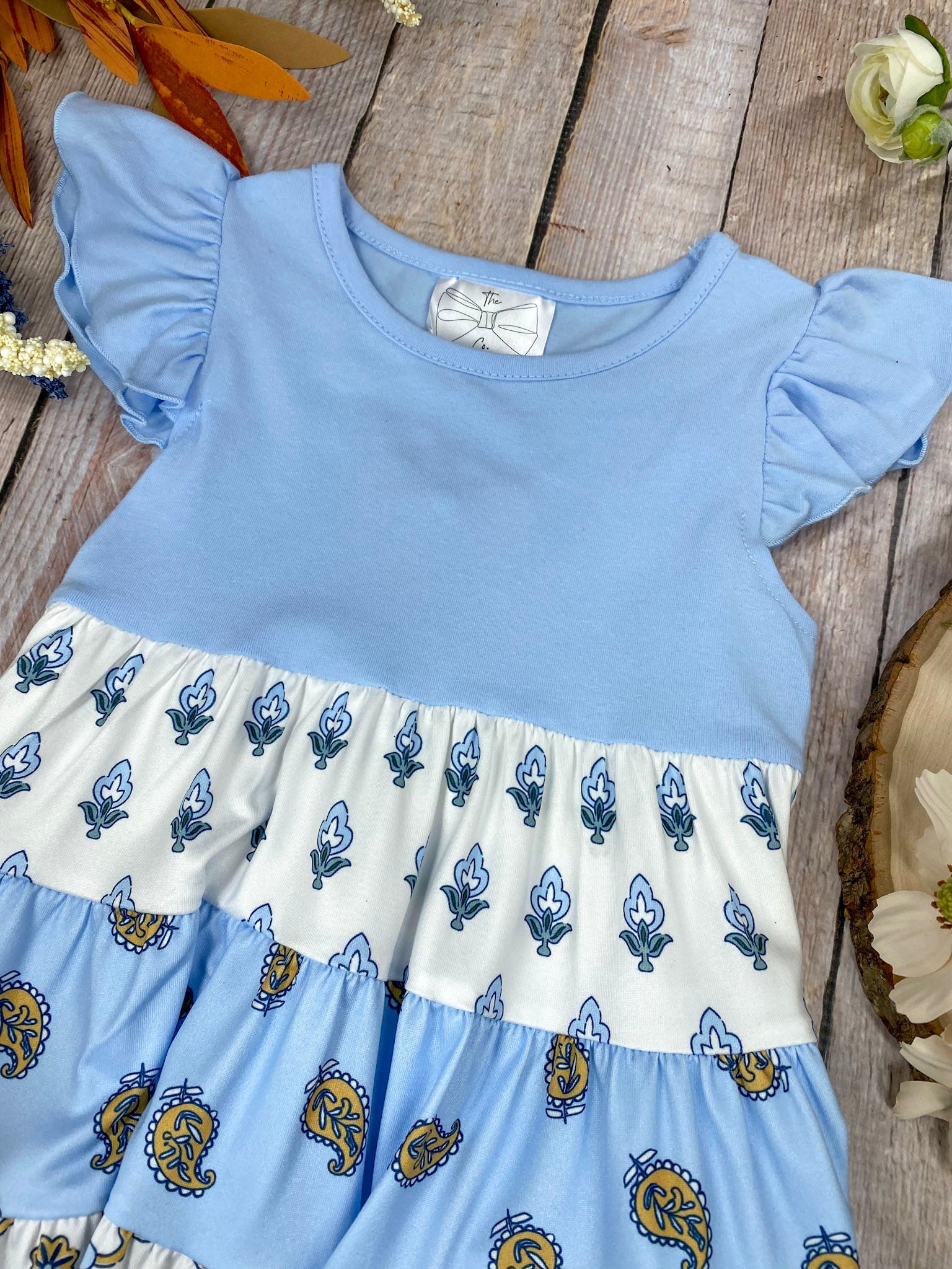 Boutique Boho Children's dress with blue top and floral skirt on a wooden background