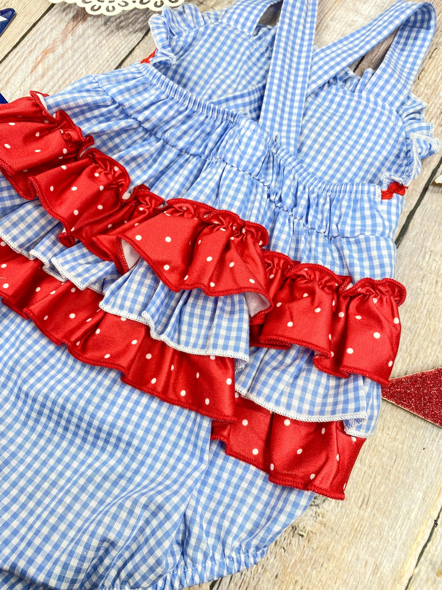 Smocked Flag Gingham Bubble Romper on a wooden background 
