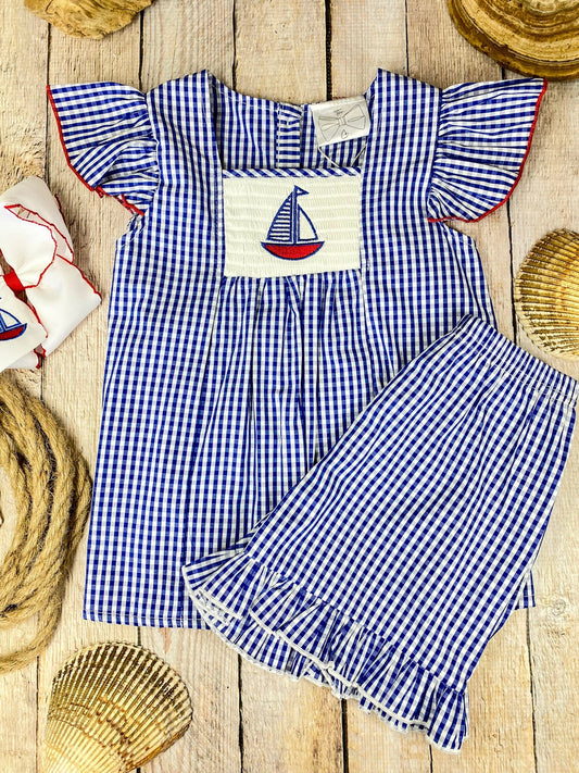 Blue checkered  top and shorts set with sailboat design on a wooden background