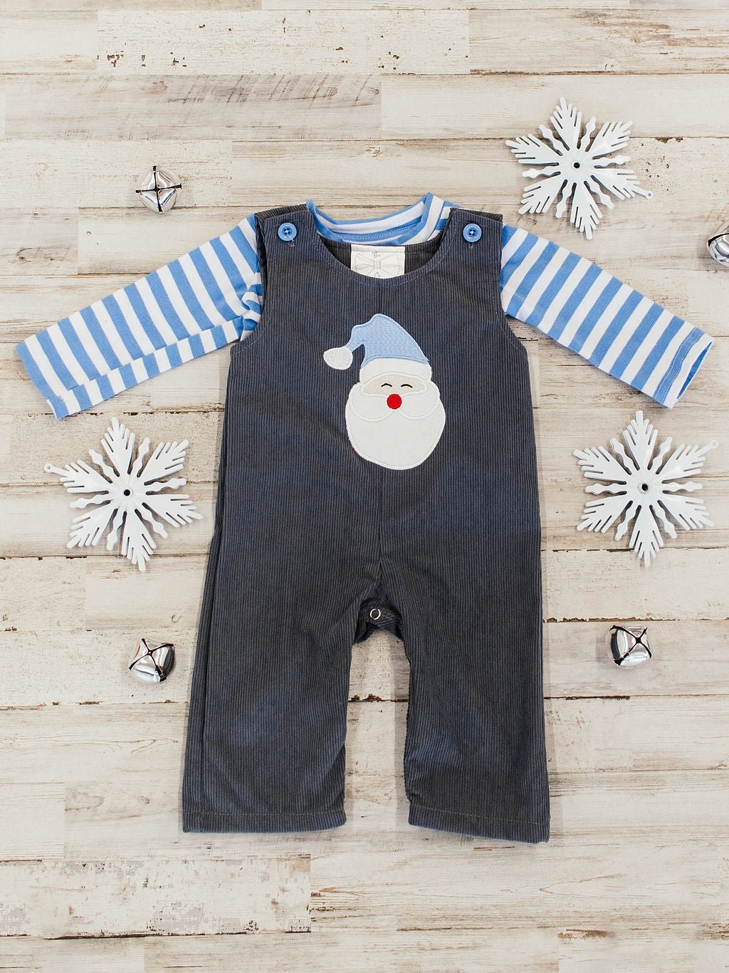 flay lay of infant outfit featuring a blue and white striped long sleeve with a dark grey corduroy overall on top that has a santa wearing a light blue hat applique