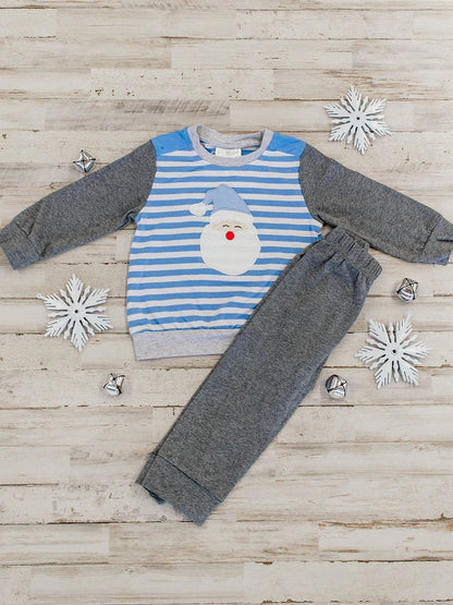 flat lay of an outfit featuring a blue and white striped long sleeve with a santa wearing blue hat applique and dark grey sleeves, paired with dark grey pants that match the sleeves
