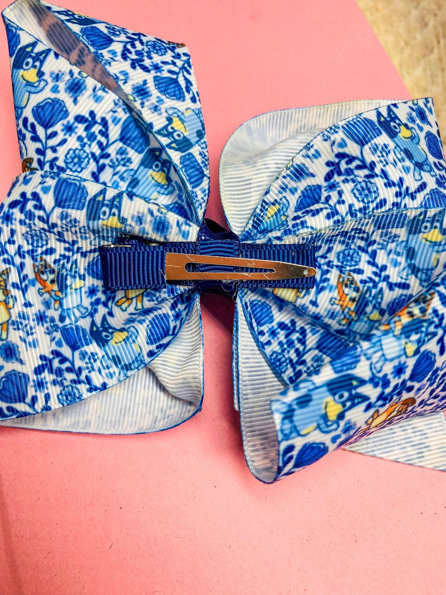 Blue floral-patterned hair bow on a pink background