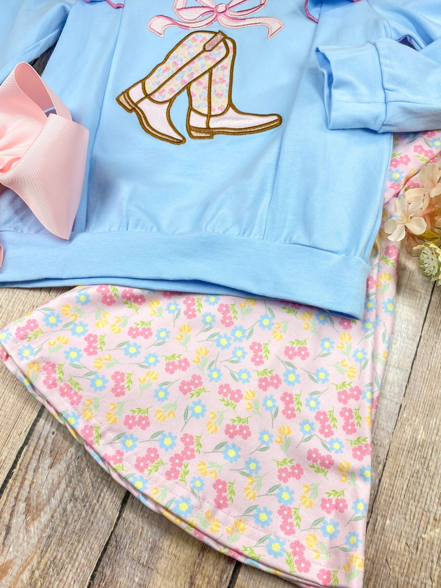 girls cowgirl two-piece with boots appliqué sweatshirt and floral bell bottoms on a wooden background