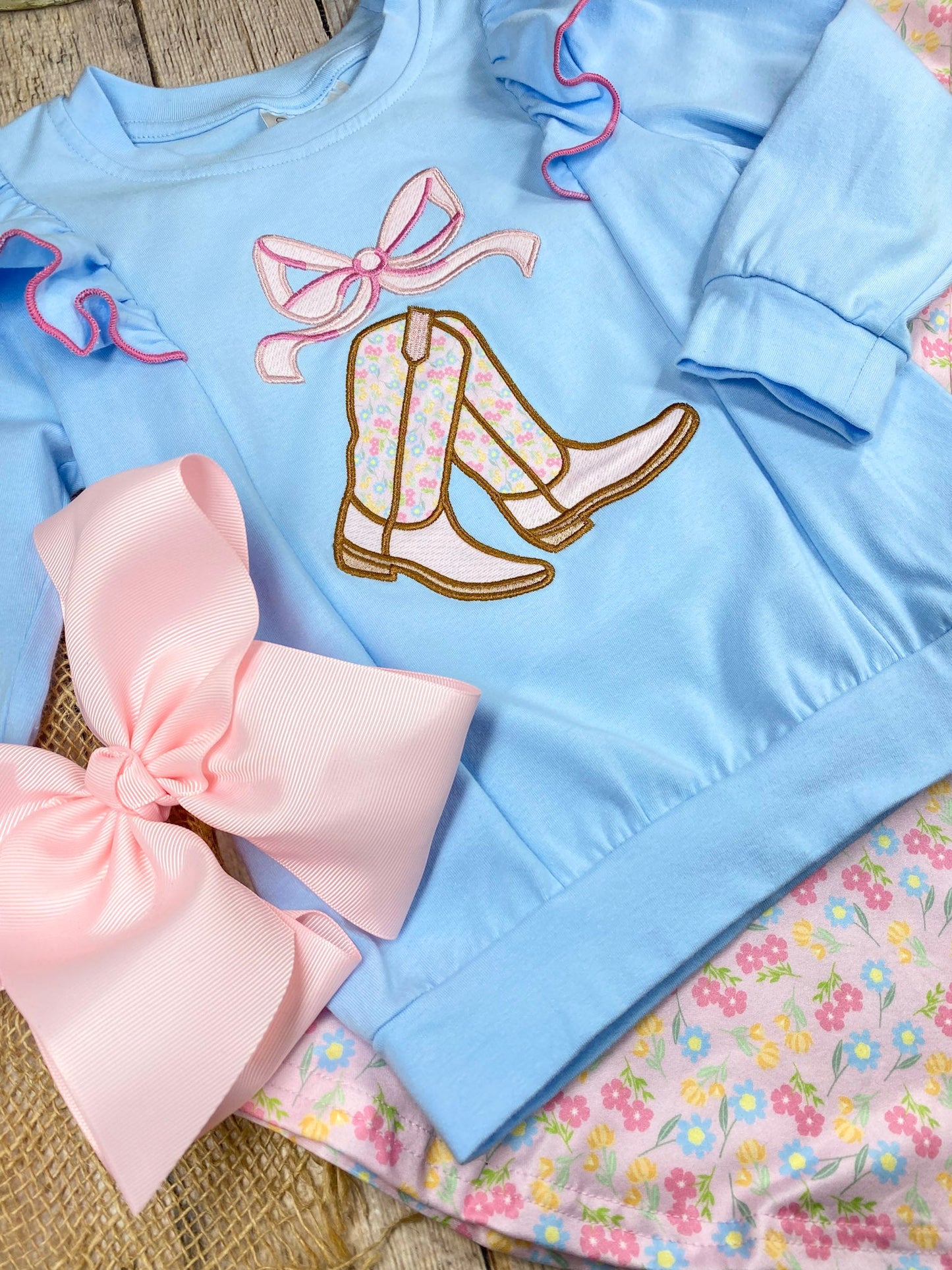 girls cowgirl two-piece with boots appliqué sweatshirt and floral bell bottoms on a wooden background