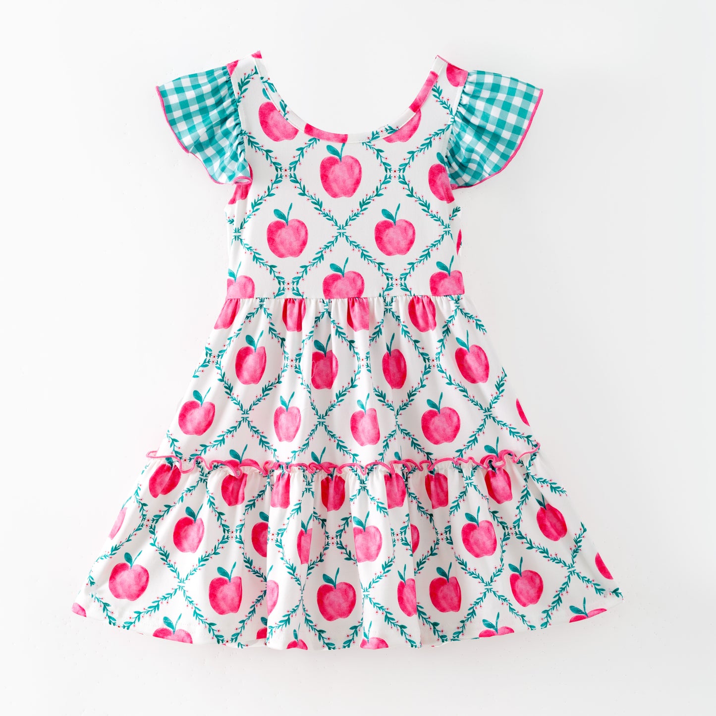 Children's dress with pink apple pattern on a white background