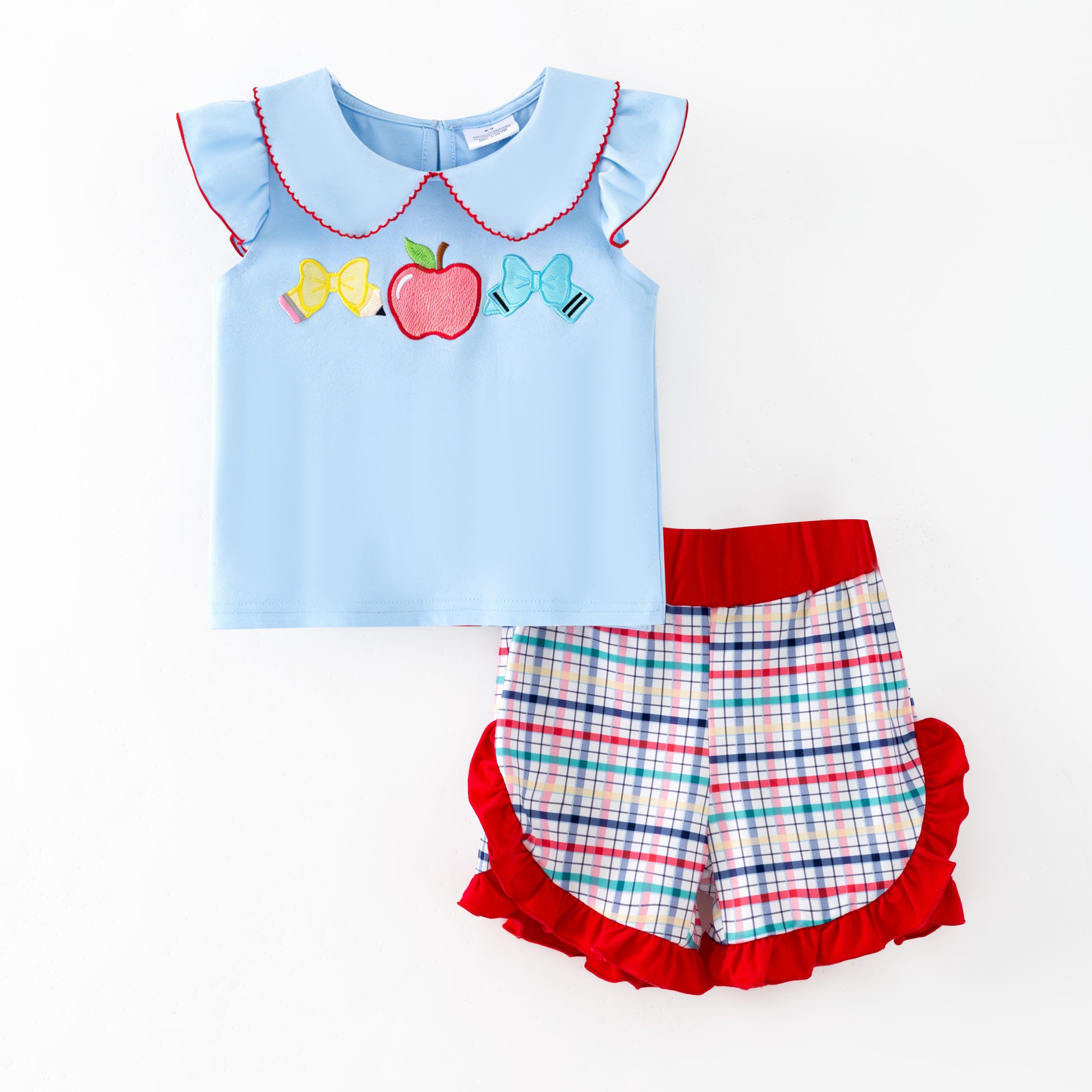 Children's outfit with light blue top and plaid shorts on a white background