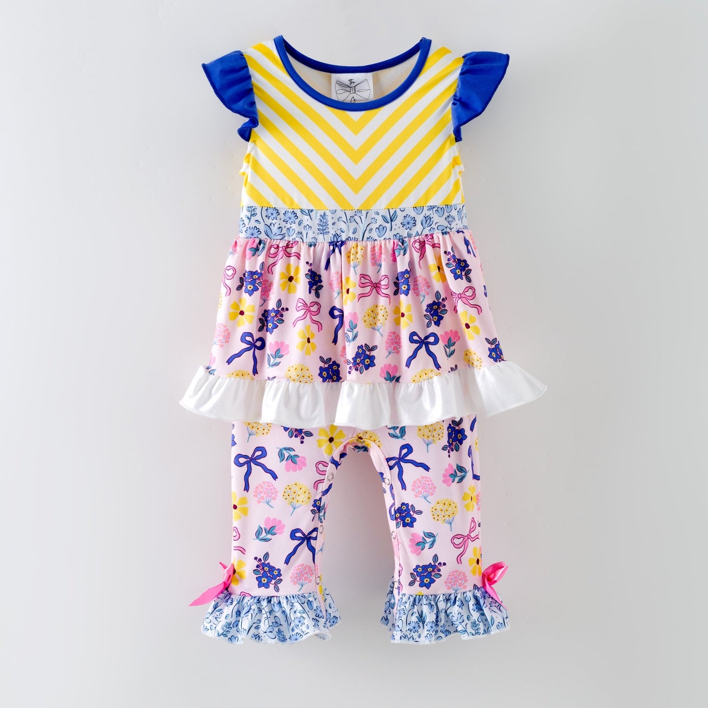 Children's outfit with yellow and purple striped top and floral pants on a gray background