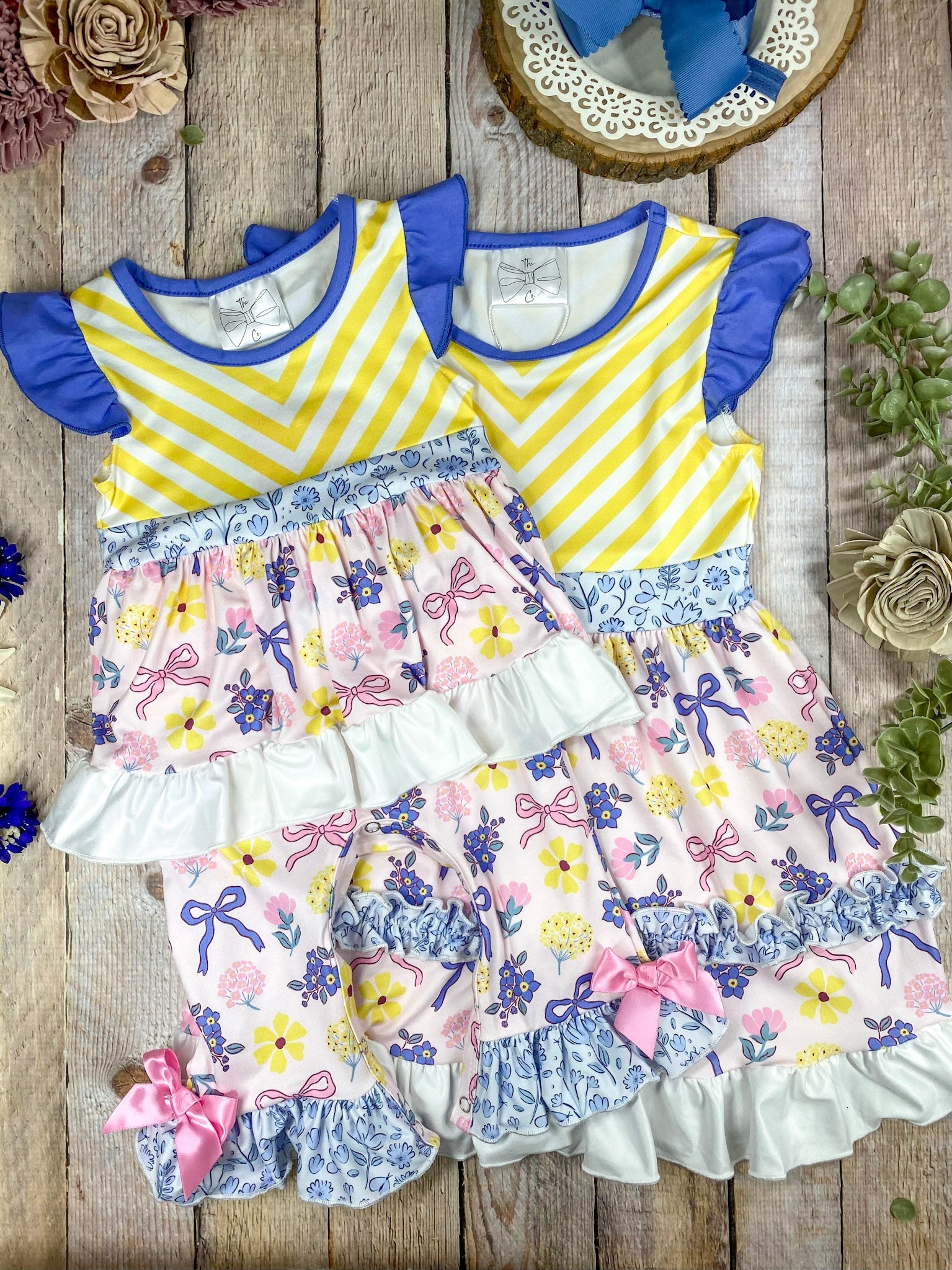 Children's outfit with yellow and purple striped top and floral pants on a wooden background