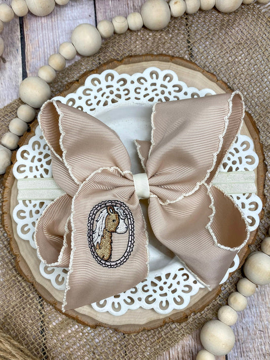 Beige bow with embroidered design on a decorative wooden board with beads. - Alternative view