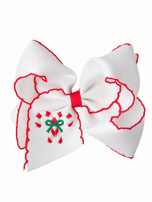 White moonstitch hair bow with red stitched edges and two embroidered candy canes tied with a green bow on the tail, on a white background
