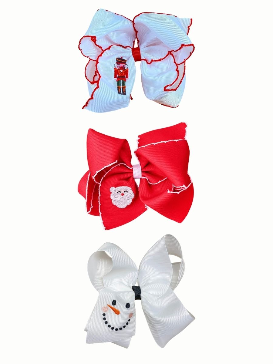 Three embroidered Christmas hair bows stacked on a white background: a white nutcracker bow with red moonstitch edges, a red Santa face bow with white moonstitch edges, and a white snowman face bow
