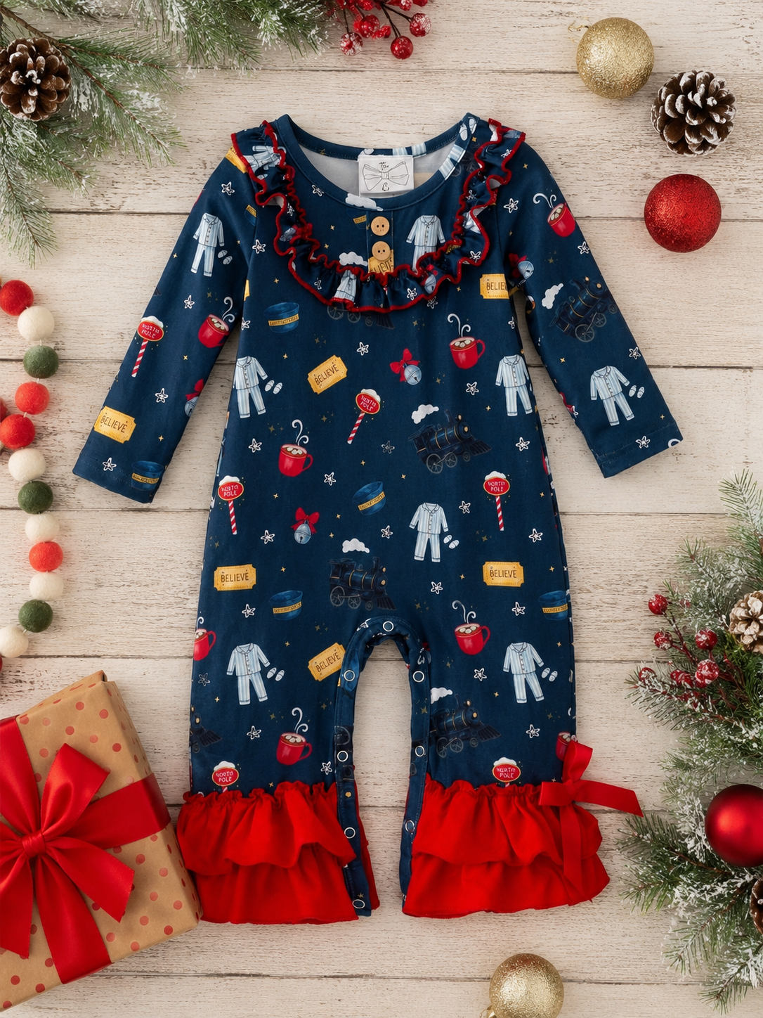 Girls Christmas train infant romper with red ruffle trim, wooden buttons, and vintage holiday train print.
