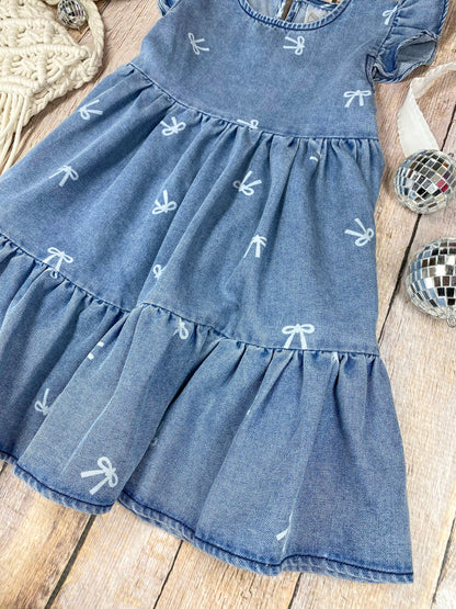 Blue denim bow print dress with ruffled sleeves and bottom on a wooden surface