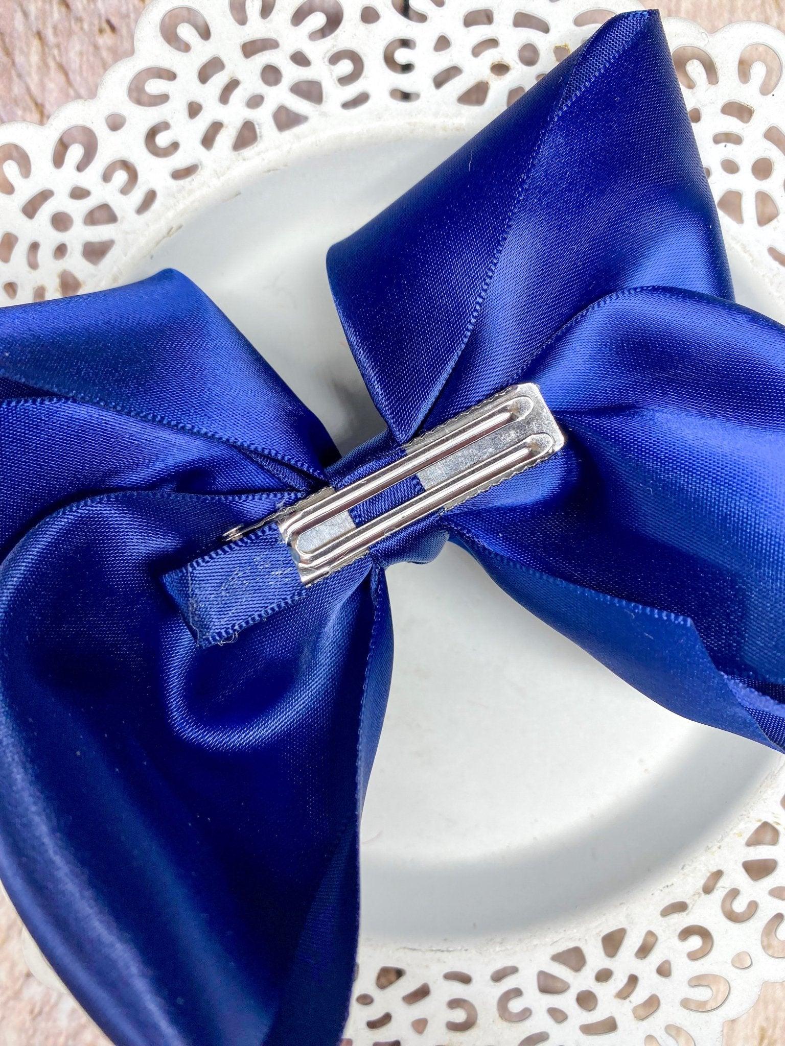 Blue satin bow with a silver clip on a decorative white background
