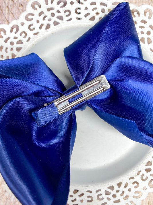 Blue satin bow with a silver clip on a decorative white background - Alternative view