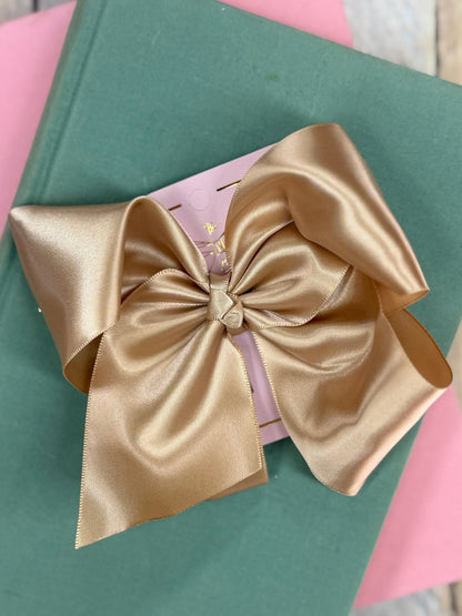 Gold satin bow on a green box with a pink background