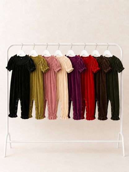 Baby girl smocked velvet holiday rompers in eight colors hanging on a clothing rack
